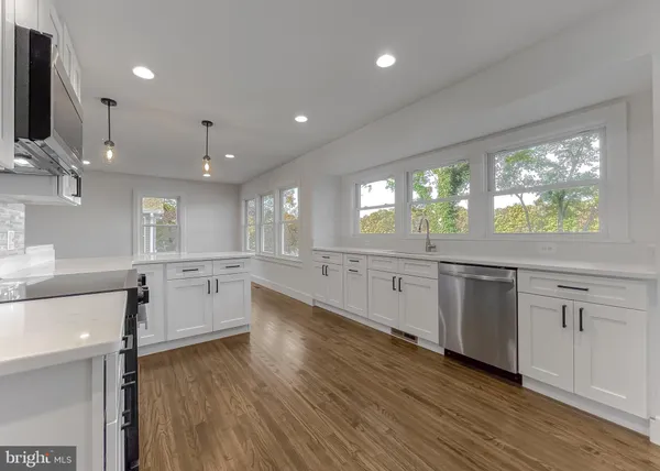 an empty room with wooden floor a ceiling fan and windows