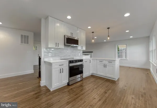 a view of an empty room with wooden floor and a ceiling fan