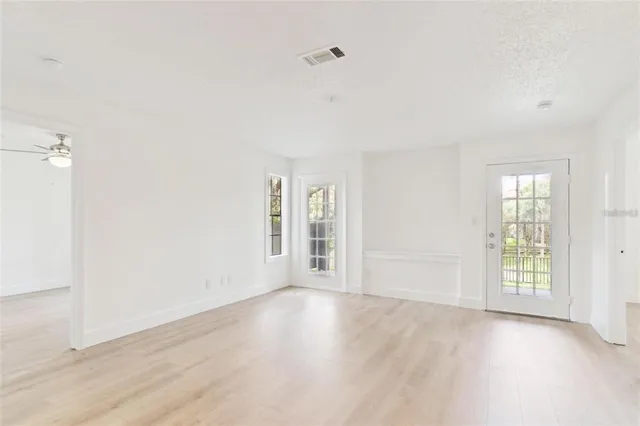an empty room with wooden floor and windows