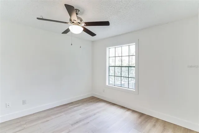an empty room with window and ceiling fan