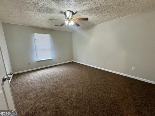 an empty room with a chandelier fan and windows