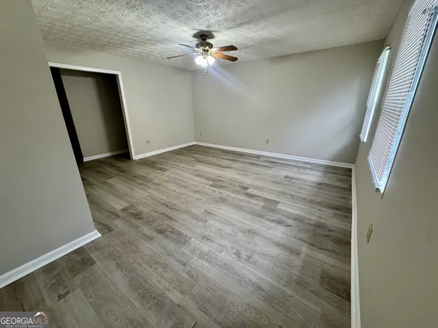 an empty room with wooden floor and fan