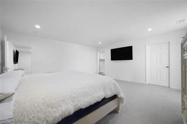 a spacious bedroom with a bed and a flat screen tv