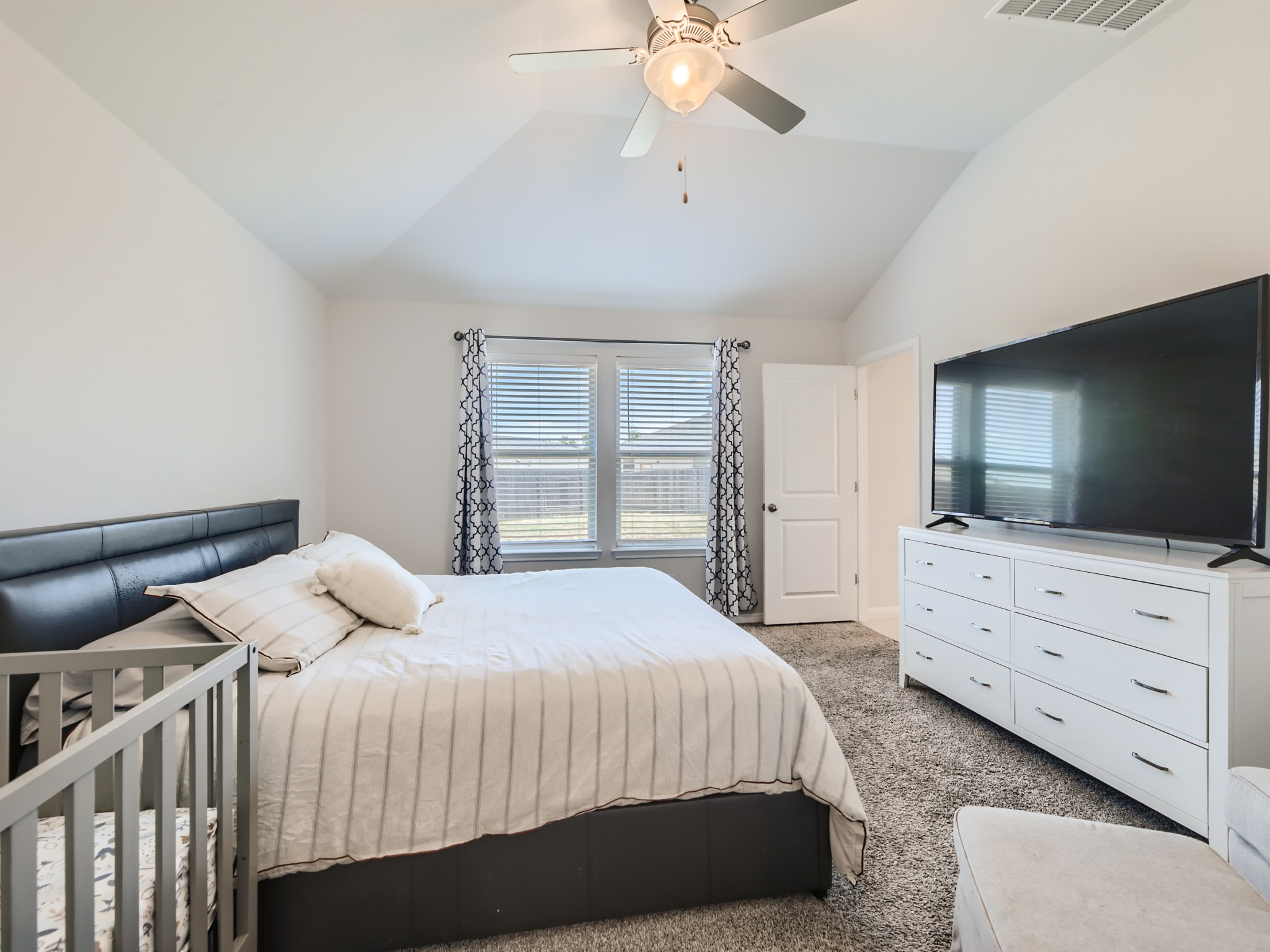 195 Star Light Way Kyle, TX 78640 - Photo 15 of 29 a bedroom with a large bed and a flat tv screen on dresser