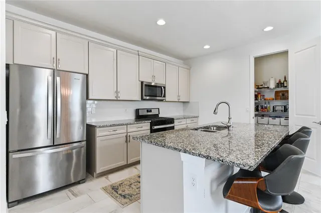 a kitchen with stainless steel appliances granite countertop a refrigerator a stove a sink and a microwave