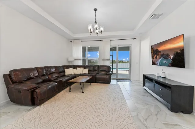 a living room with furniture a chandelier and a flat screen tv
