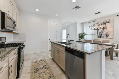 a kitchen with granite countertop stainless steel appliances a sink stove and cabinets