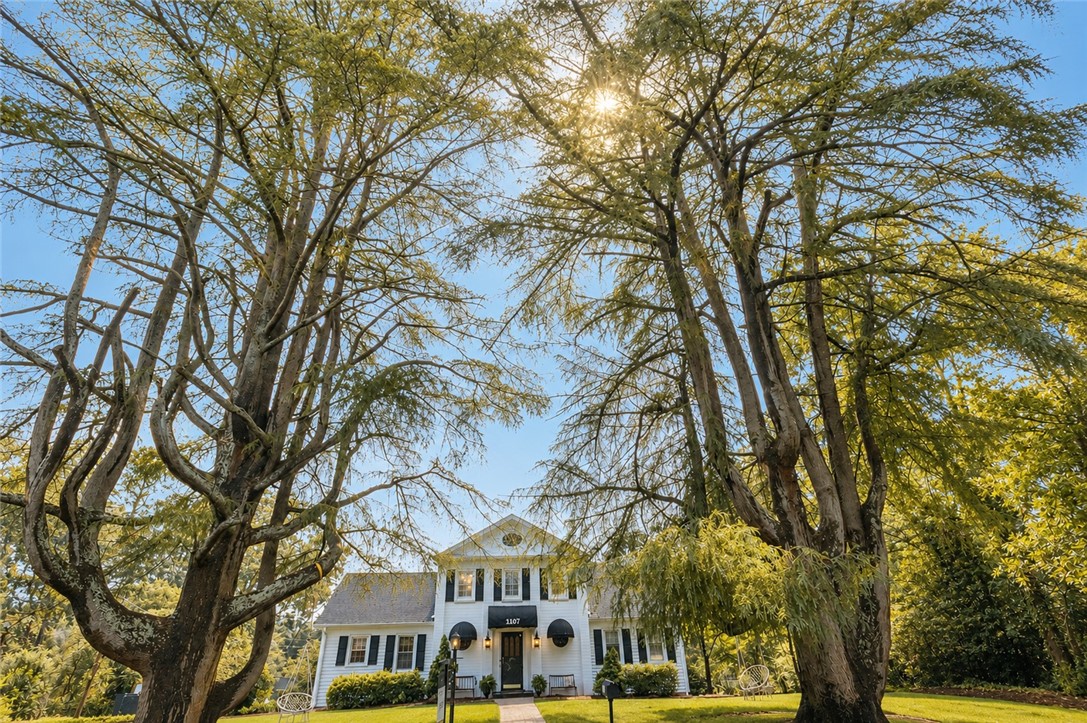 1107 Springdale Road Anderson, SC 29621 - Photo 49 of 49 Mature trees frame the classic white facade of this charming residence, offering inviting curb appeal.