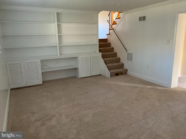 a view of an empty room with stairs and a window