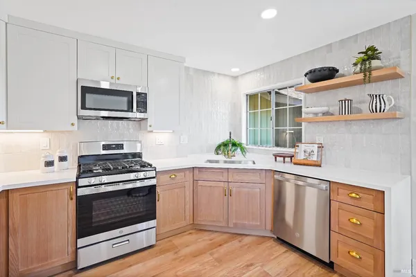 a kitchen with cabinets stainless steel appliances and wooden floor