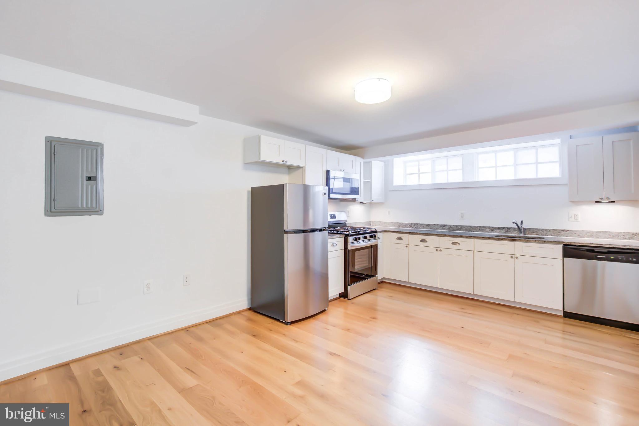 3625 16th Street Northwest, Unit B1 Washington, DC 20010 - Photo 15 of 15 a large white kitchen with stainless steel appliances granite countertop a stove a sink dishwasher and a refrigerator