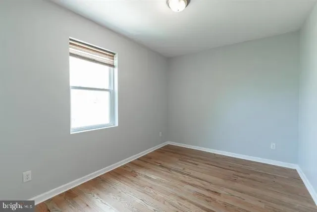 an empty room with wooden floor and a window