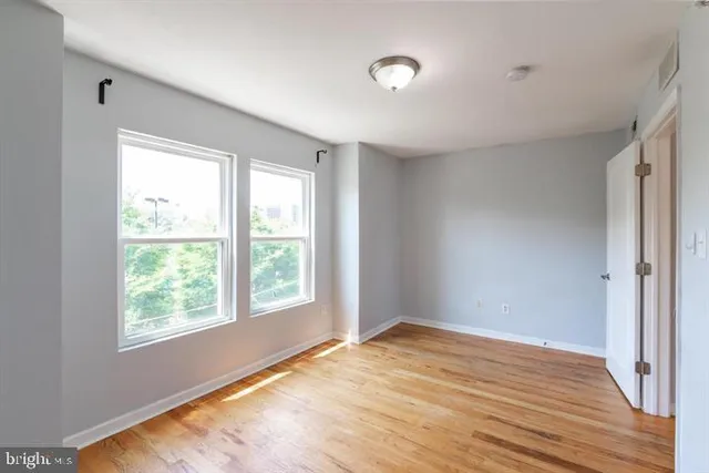 a view of an empty room with wooden floor and a window