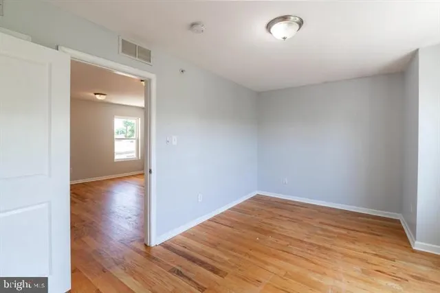 a view of empty room with wooden floor and fan