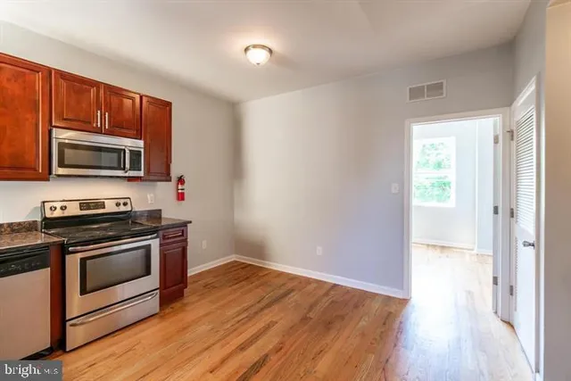 a kitchen with wooden floors and stainless steel appliances