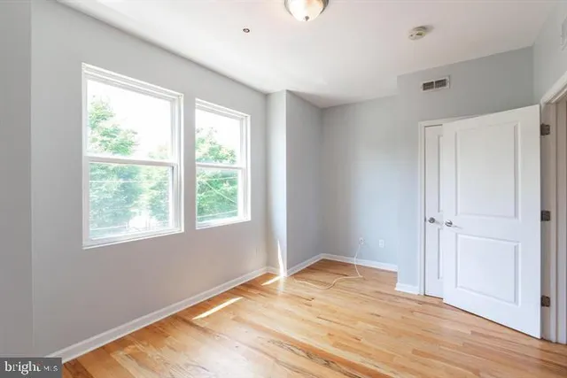 a view of empty room with wooden floor and fan