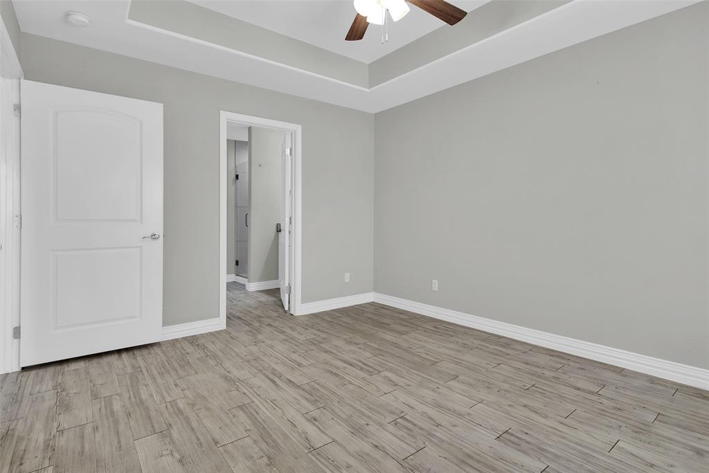 622 East Heron Street Denison, TX 75021 - Photo 16 of 20 Unfurnished bedroom with light wood-style flooring, a ceiling fan, and a tray ceiling