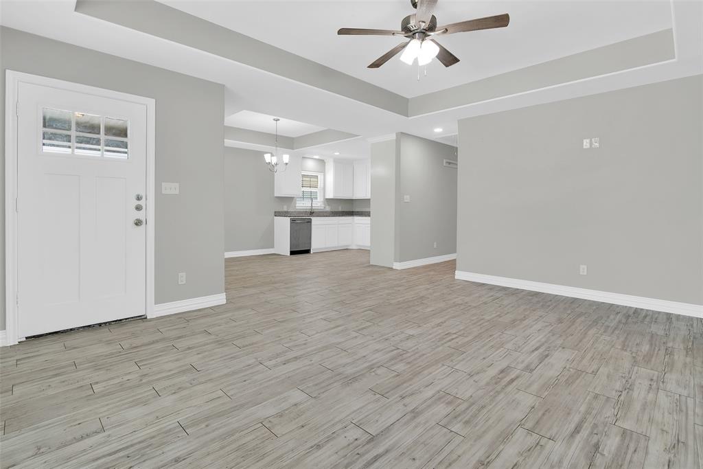 622 East Heron Street Denison, TX 75021 - Photo 3 of 20 Unfurnished living room with a tray ceiling, light wood-style floors, and a chandelier