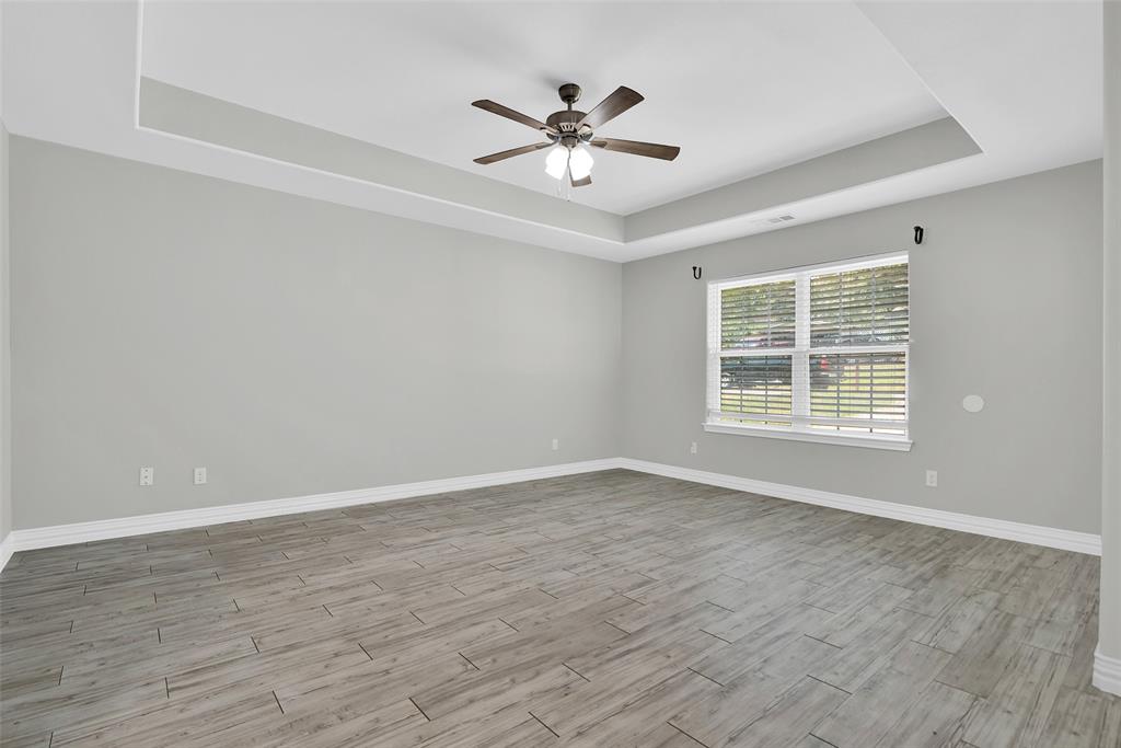 622 East Heron Street Denison, TX 75021 - Photo 4 of 20 Unfurnished room with a raised ceiling, light wood-type flooring, and a ceiling fan