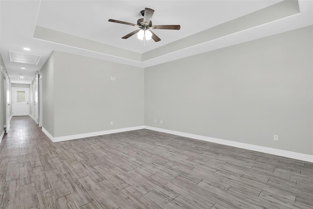 622 East Heron Street Denison, TX 75021 - Photo 6 of 20 Unfurnished room with a tray ceiling, wood finished floors, attic access, ceiling fan, and recessed lighting