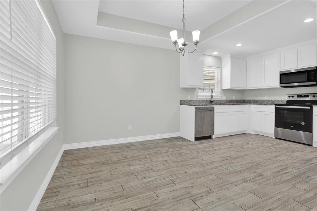 622 East Heron Street Denison, TX 75021 - Photo 7 of 20 Kitchen with appliances with stainless steel finishes, decorative light fixtures, light wood-style floors, white cabinetry, and a chandelier