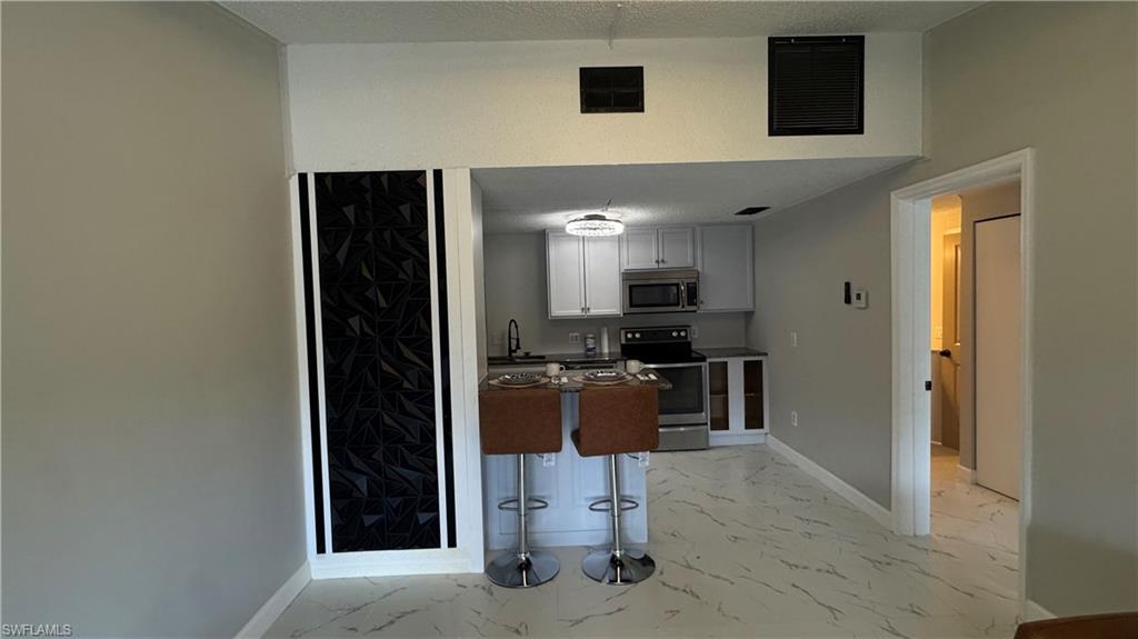 5222 Treetops Drive Naples, FL 34113 - Photo 5 of 9 a kitchen with stainless steel appliances kitchen island granite countertop a refrigerator and a stove top oven