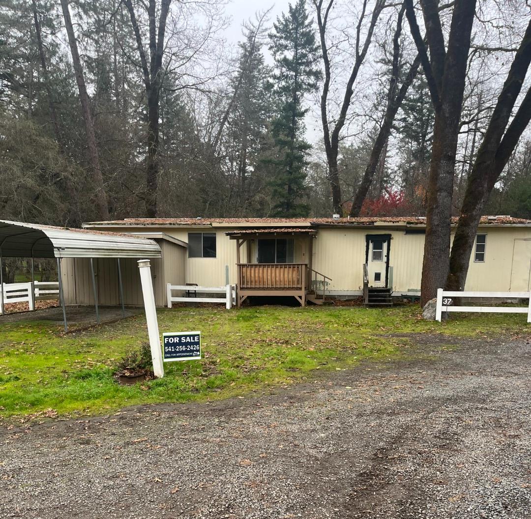 a view of a house with a yard and large tree