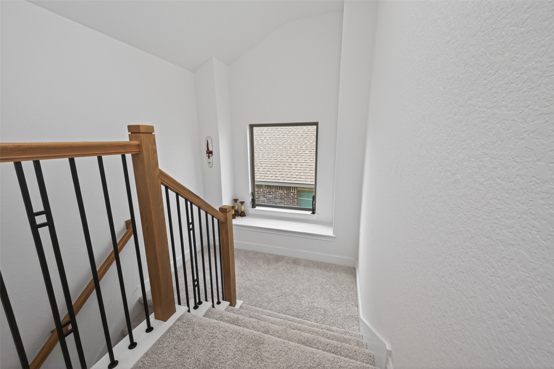 20802 Mirror Point Drive Cypress, TX 77433 - Photo 21 of 37 The staircase features a wooden handrail complemented by sleek, black metal balusters. The carpeted stairs descend to a comfortable nook, while crisp, white walls enhance the clean and bright atmosphere.