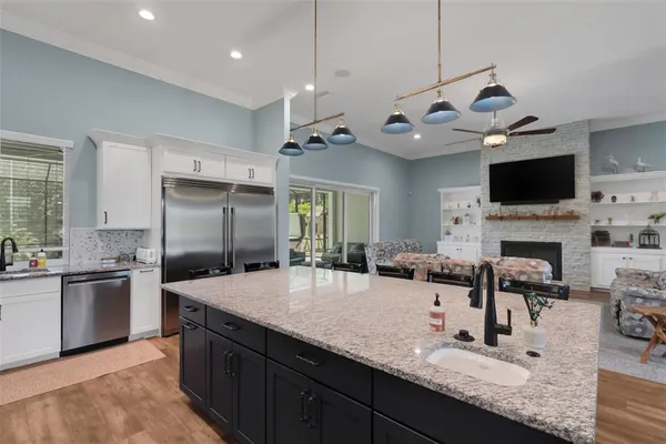 a kitchen with granite countertop a sink a counter top stainless steel appliances and cabinets