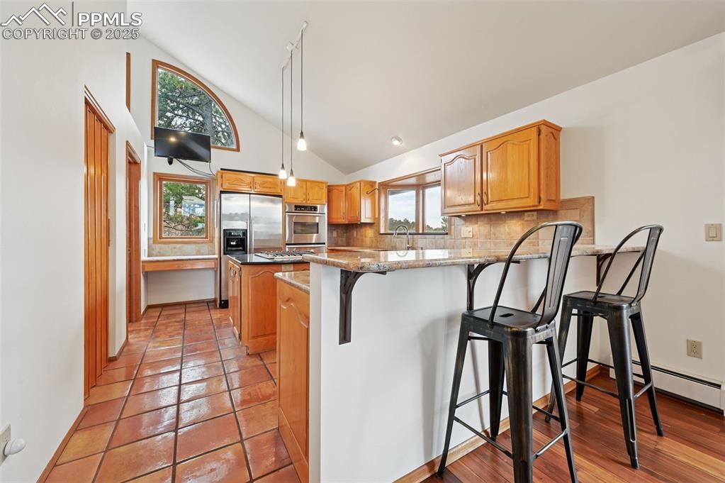 17580 Chipped Arrow Way Monument, CO 80132 - Photo 24 of 50 a kitchen with stainless steel appliances granite countertop a table chairs and a refrigerator