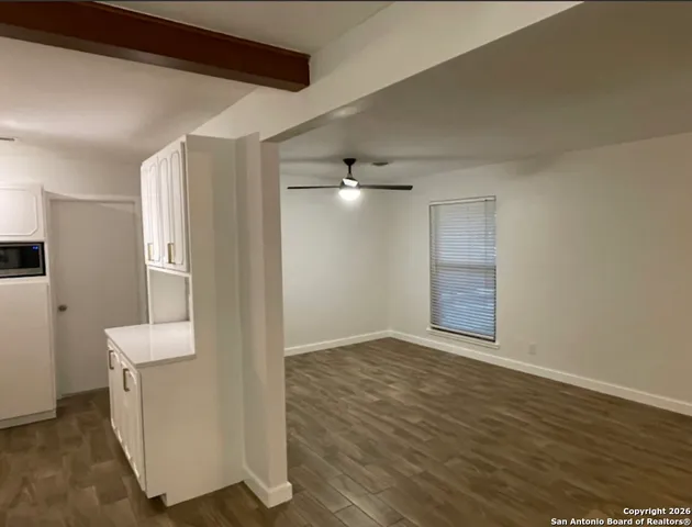 a view of an empty room with wooden floor and a window