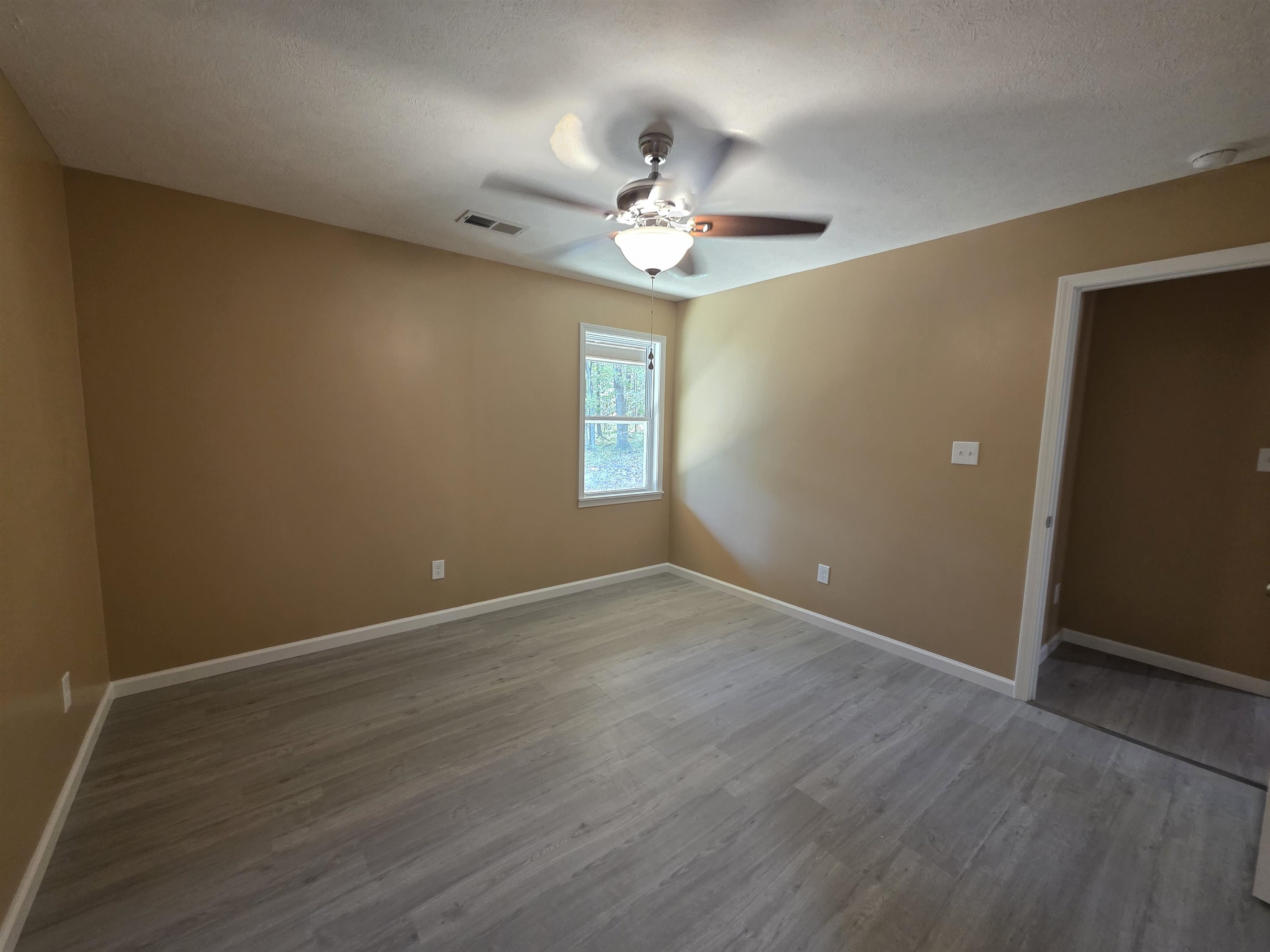 1020 Jade Road Savannah, TN 38372 - Photo 8 of 16 an empty room with wooden floor chandelier fan and windows