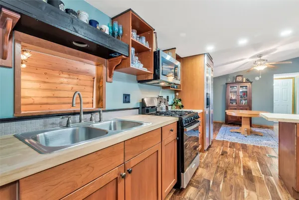 a kitchen with stainless steel appliances granite countertop a refrigerator a stove and a sink with wooden floor