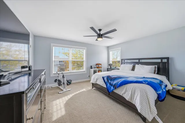 a spacious bedroom with a bed a table and large windows