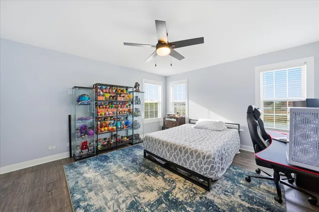 a bedroom with a bed a desk and chair with the wooden floor