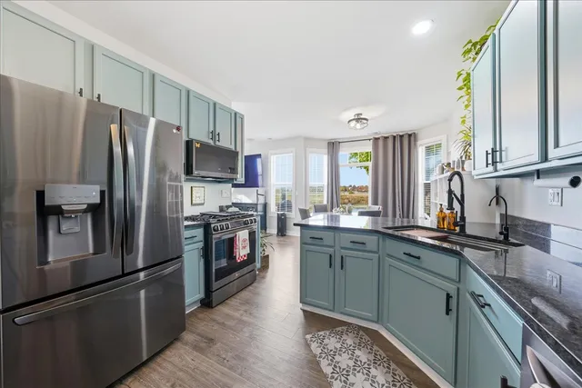 a kitchen with stainless steel appliances granite countertop a refrigerator a sink a stove a washer dryer and a refrigerator