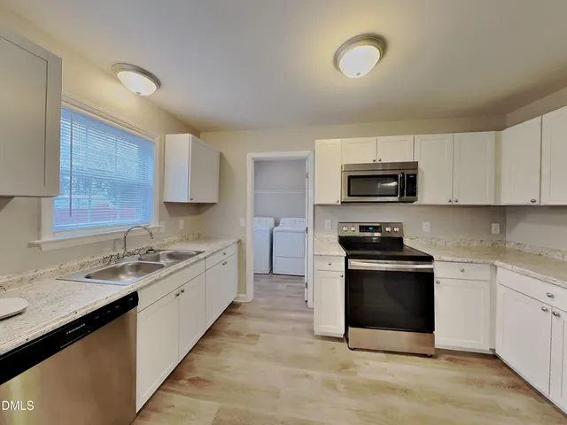 a kitchen with stainless steel appliances granite countertop a sink stove microwave and refrigerator