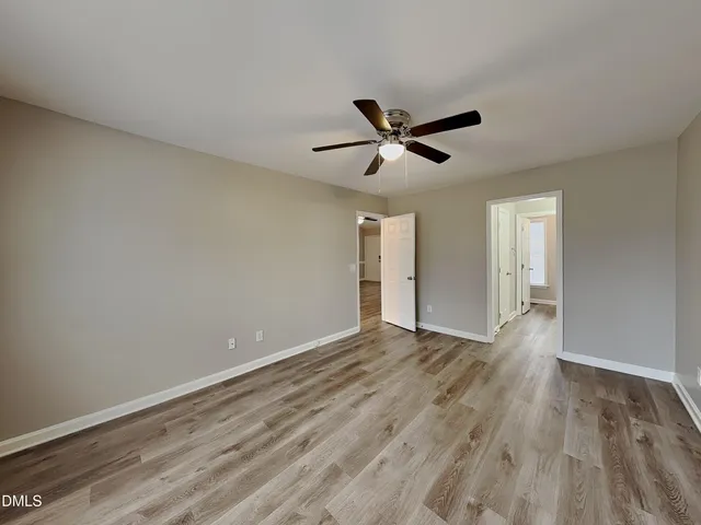 a view of empty room with wooden floor and ceiling fan