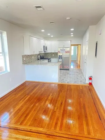 a view of a kitchen with kitchen island a sink wooden floor and a living room view