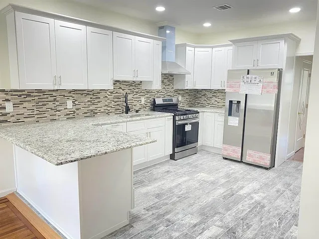 a kitchen with stainless steel appliances granite countertop a stove a sink and a refrigerator
