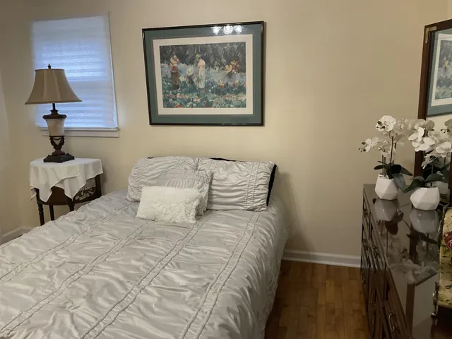 a bedroom with a bed and a lamp on dresser