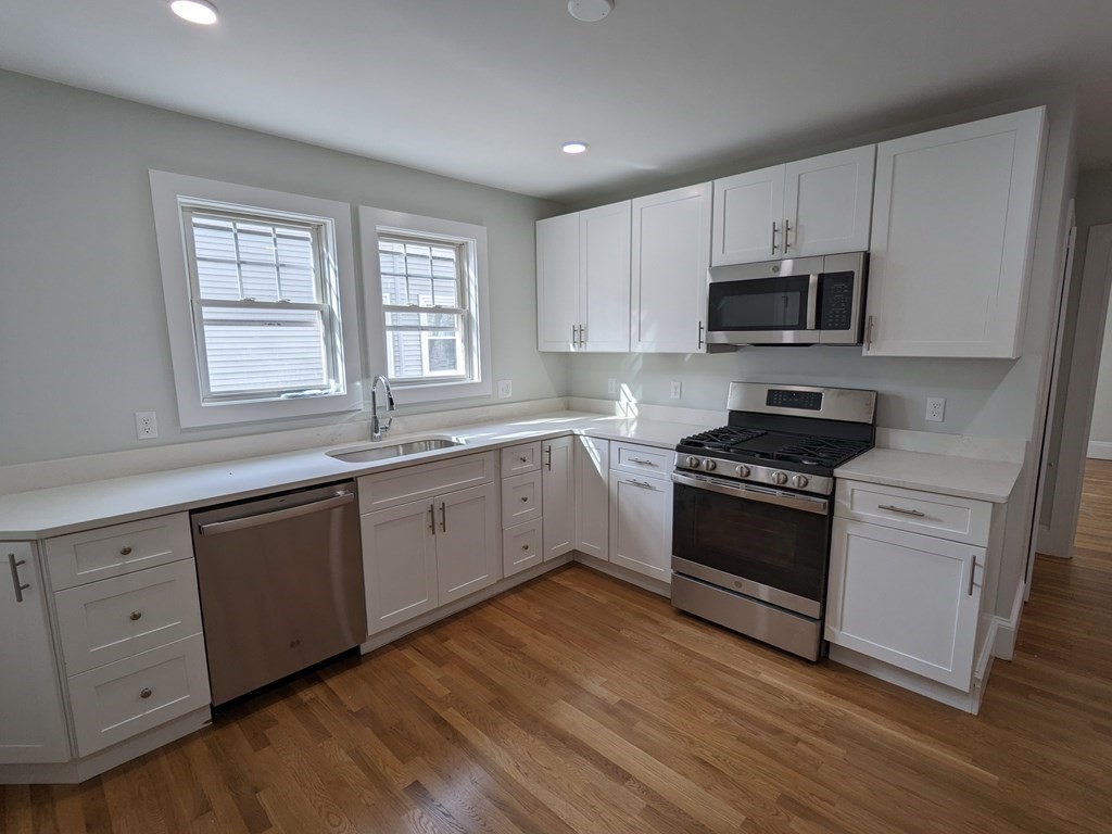 a kitchen with stainless steel appliances white cabinets a sink and a stove