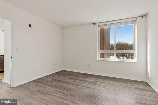 a view of empty room with window and wooden floor