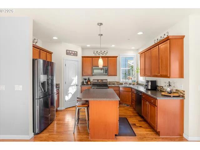 a kitchen with stainless steel appliances granite countertop a refrigerator a stove top oven and a sink