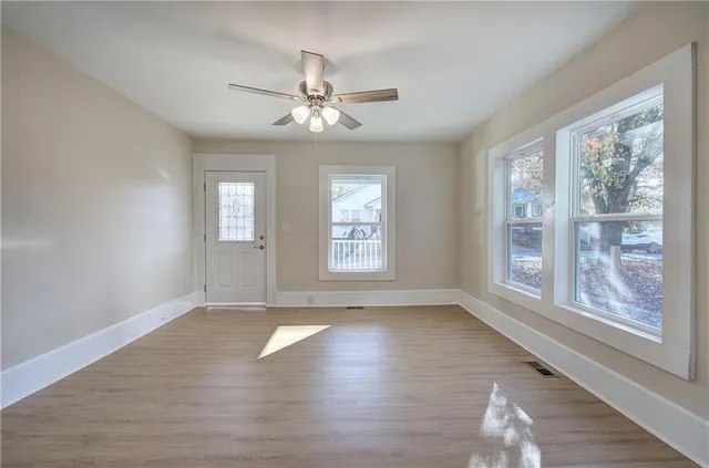 a view of an empty room with wooden floor and a window