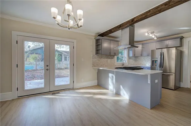 a kitchen with stainless steel appliances granite countertop a refrigerator a sink dishwasher a stove and white cabinets with wooden floor