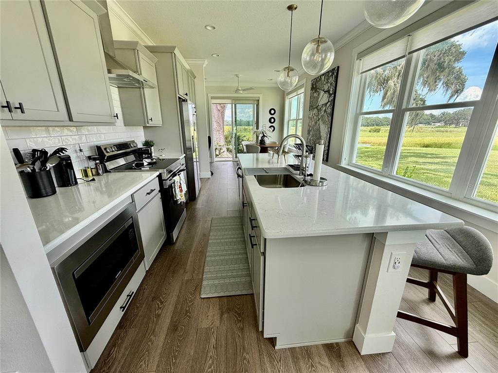 12030 Lakeshore Way Oxford, FL 34484 - Photo 5 of 38 a kitchen with stainless steel appliances a stove a sink dishwasher and white cabinets with wooden floor