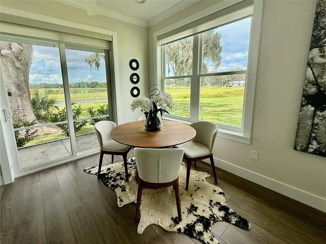 a dining room with wooden floor and large windows