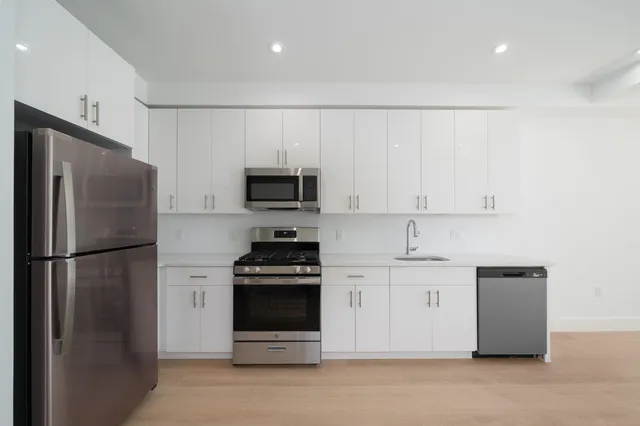 a kitchen with stainless steel appliances white cabinets and a refrigerator