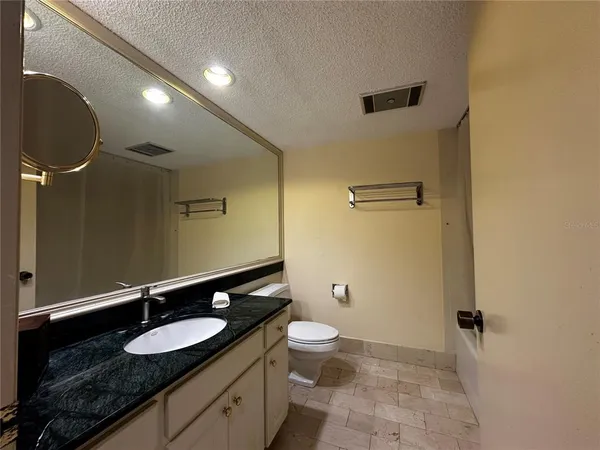 a bathroom with a granite countertop sink a toilet and a mirror